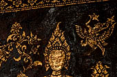 Wat Xieng Thong temple in Luang Prabang, Laos. Detail of the  intricate gold stencilling on black lacquer that decorate the walls of the sim. 